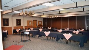 A conference room with multiple tables, chairs, and a podium. - Hot Springs Hotel and Spa (Thermopolis)