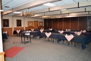 A conference room with multiple tables, chairs, and a podium.