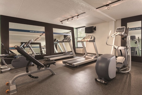 Une salle de sport équipée de tapis de course, de vélos elliptiques et de matériel de musculation.
