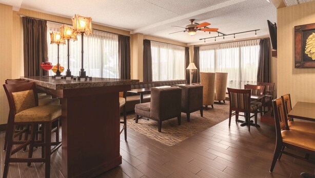 A spacious hotel lobby with a central bar, seating area, and a ceiling fan. - Hampton Inn Des Moines-Airport (Des Moines)