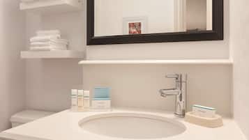 A bathroom with a white sink, a mirror with a black frame, and a shelf with folded towels.