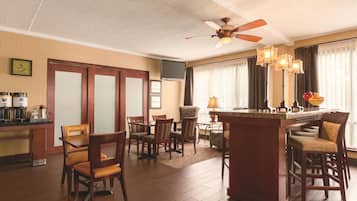 Een hotelkamer met een eethoek, een bar en een plafondventilator.