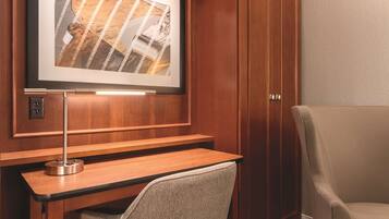 A wooden desk with a framed picture above it, a chair, and a cabinet.