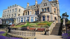 A large, historic stone building with multiple stories, a prominent turret, and a curved bay window. - Culloden Estate & Spa (Holywood)