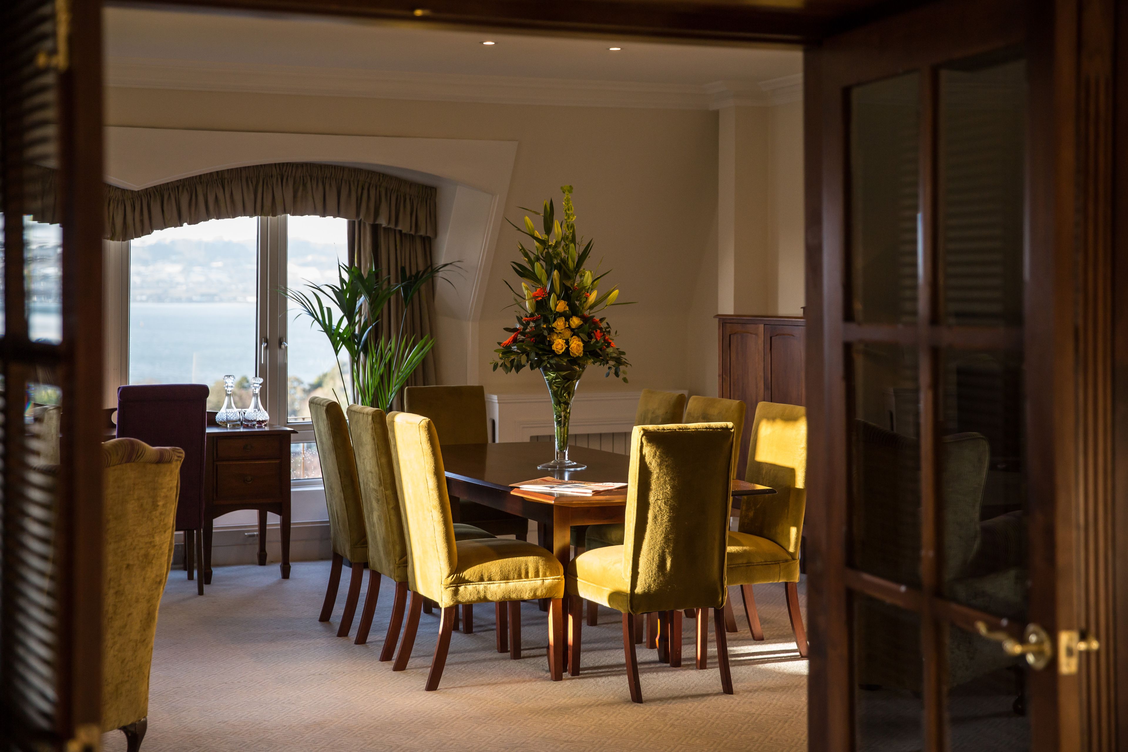 A dining area with a table, chairs, and a vase of flowers.