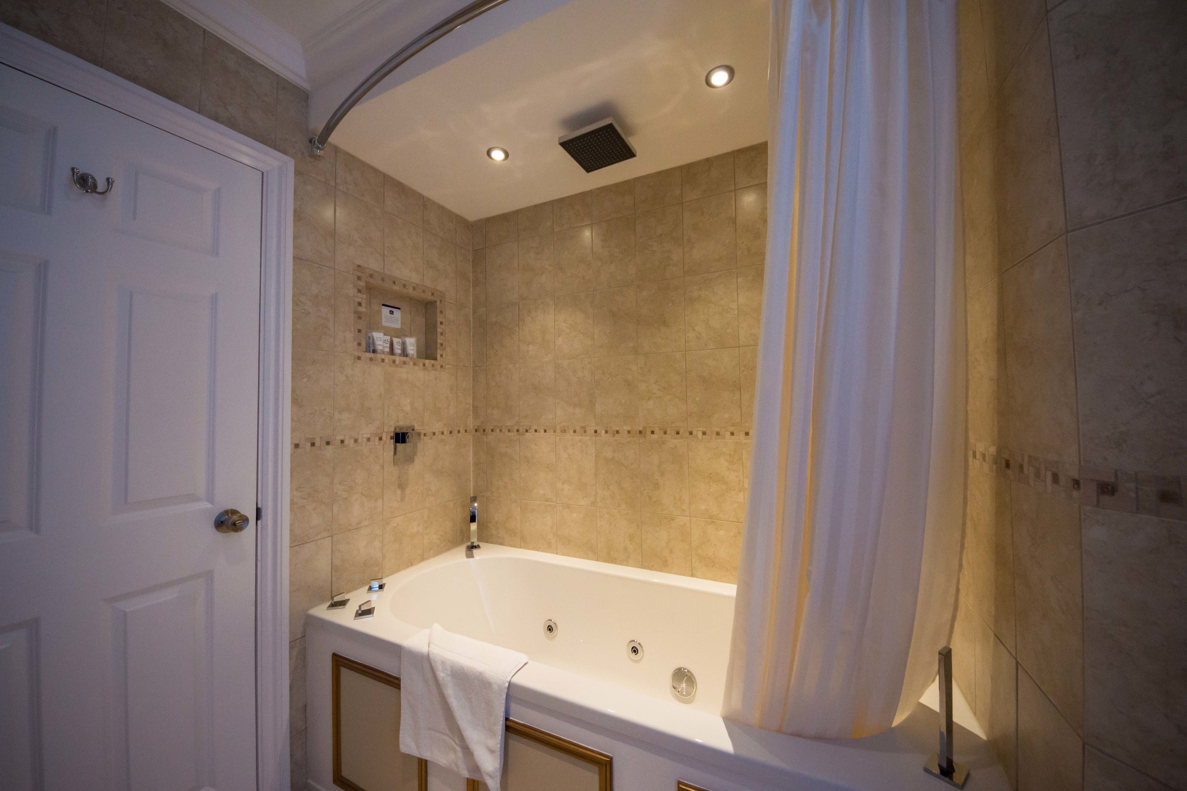 A bathroom with a bathtub, a shower, and a door.