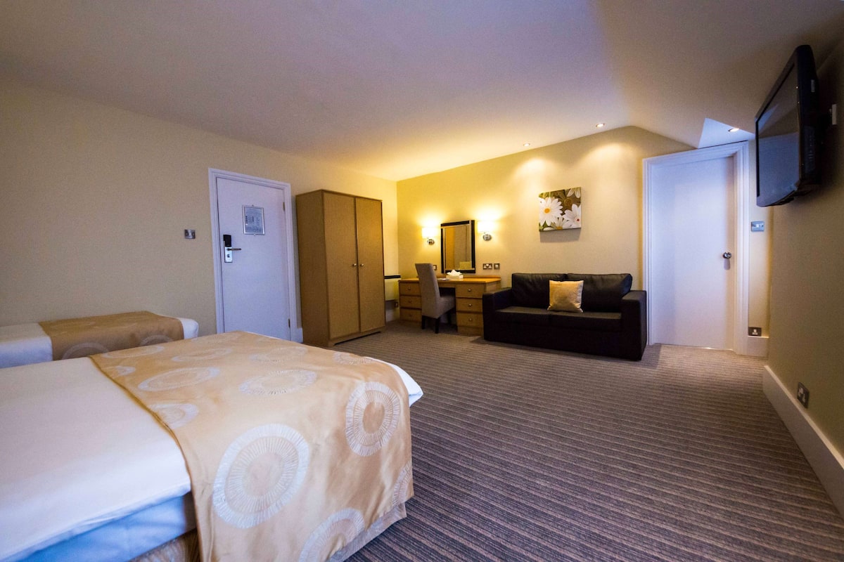 Een hotelkamer met een bed, een bureau, een bank en een televisie.