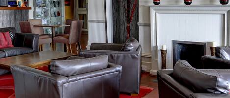 Una sala de estar moderna con sofás de cuero, una mesa de comedor con superficie de vidrio y una chimenea.