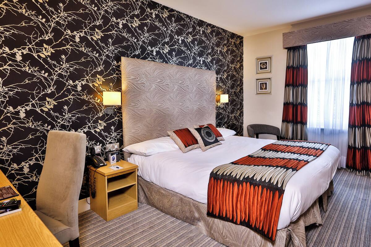 Een hotelkamer met een groot bed, een bureau, een stoel en een klein tafeltje.