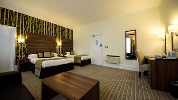 A hotel room with two beds, a desk, a chair, a coffee maker, and a mirror.