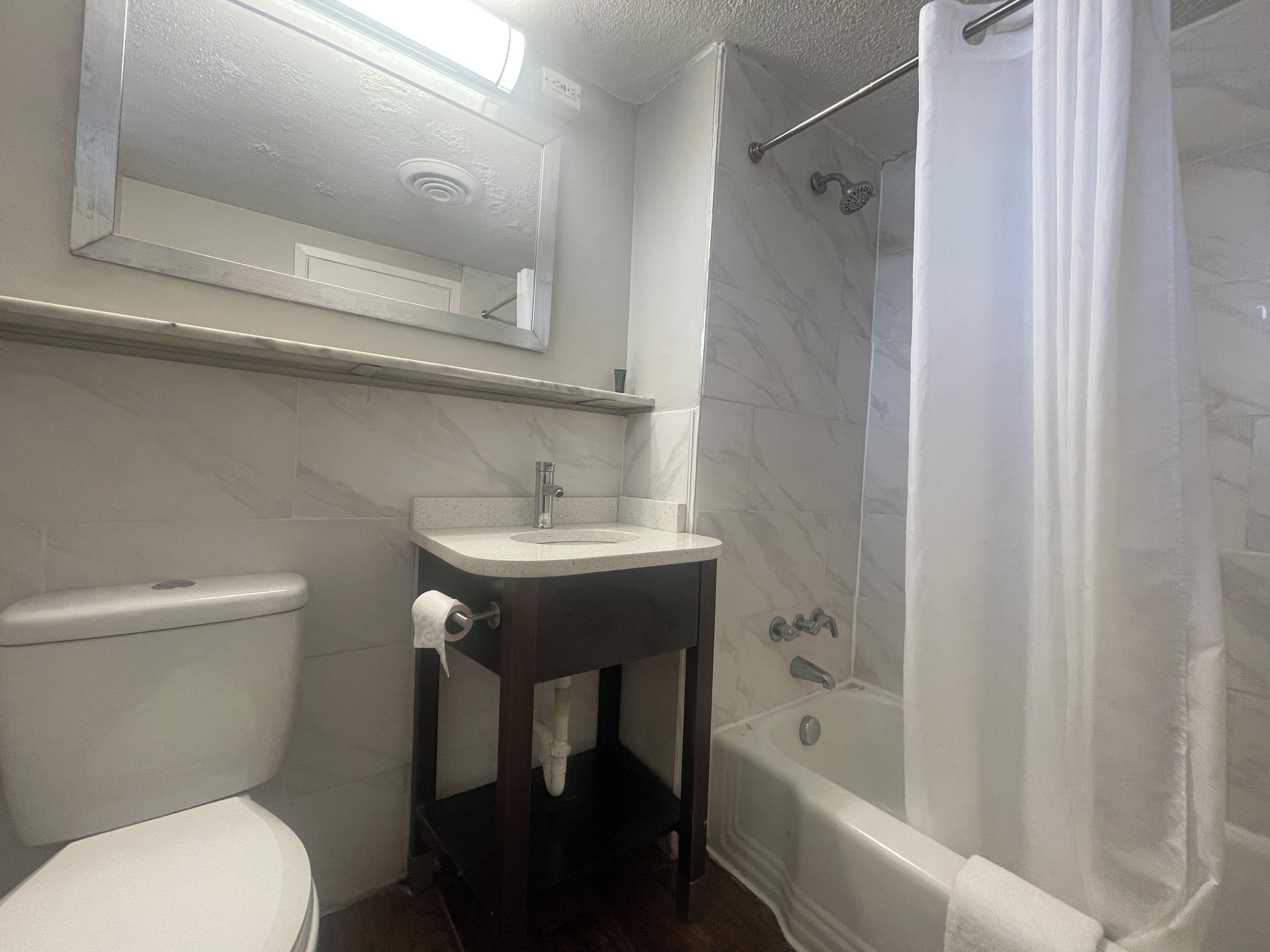 A bathroom with a toilet, sink, and shower.