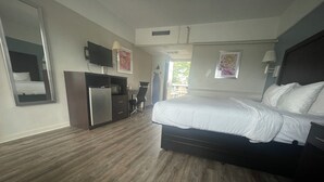 Una habitación de hotel con una cama, un escritorio, una silla, un televisor y una ventana.