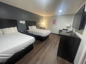 Une chambre d’hôtel avec deux lits, un bureau, une télévision et une lampe.