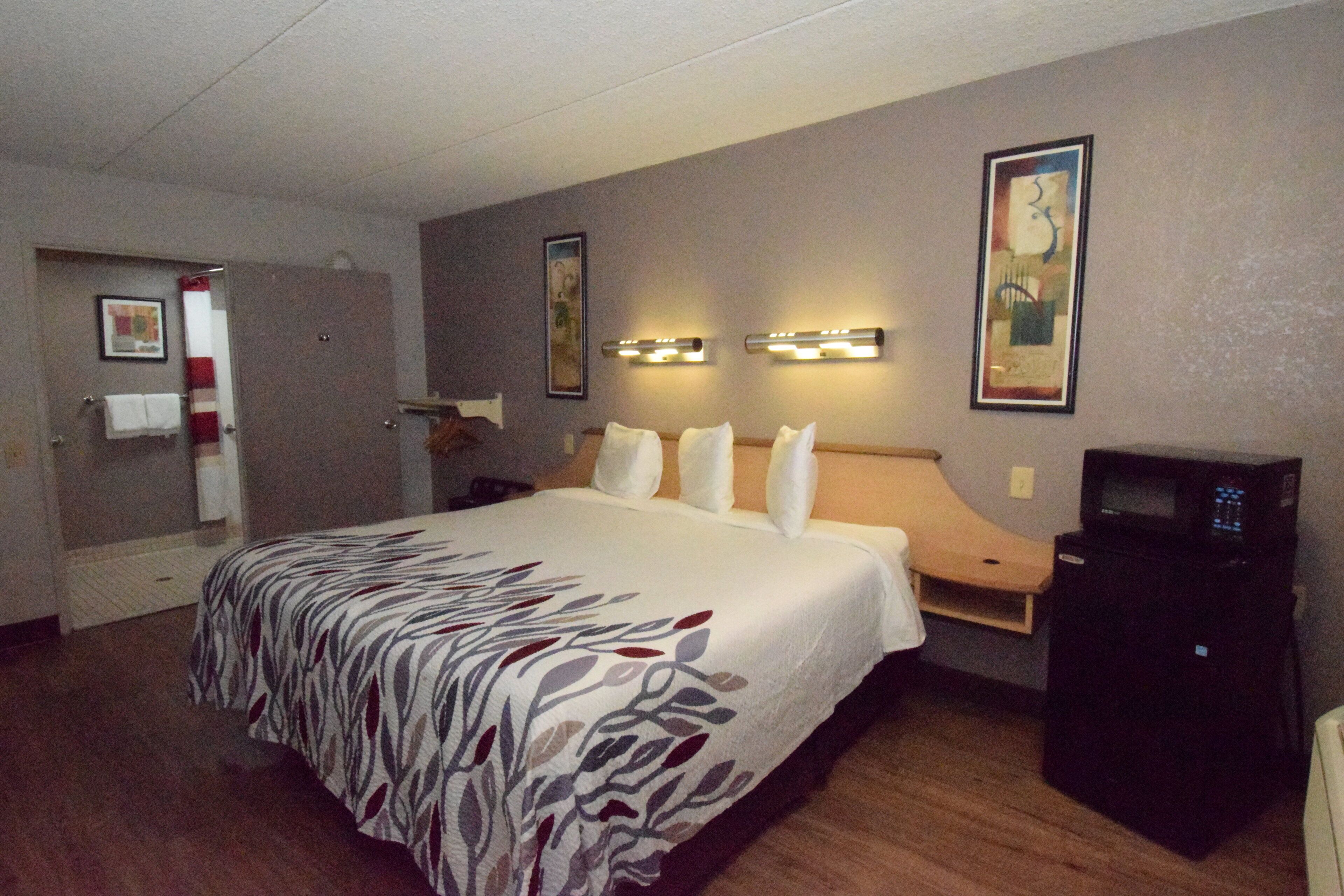 Una habitación de hotel con una cama grande, un escritorio con una computadora y un microondas.