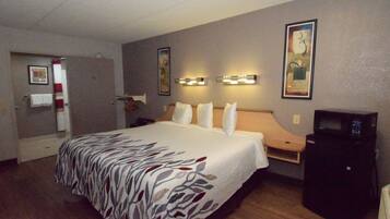 A hotel room with a large bed, a desk with a computer, and a microwave.