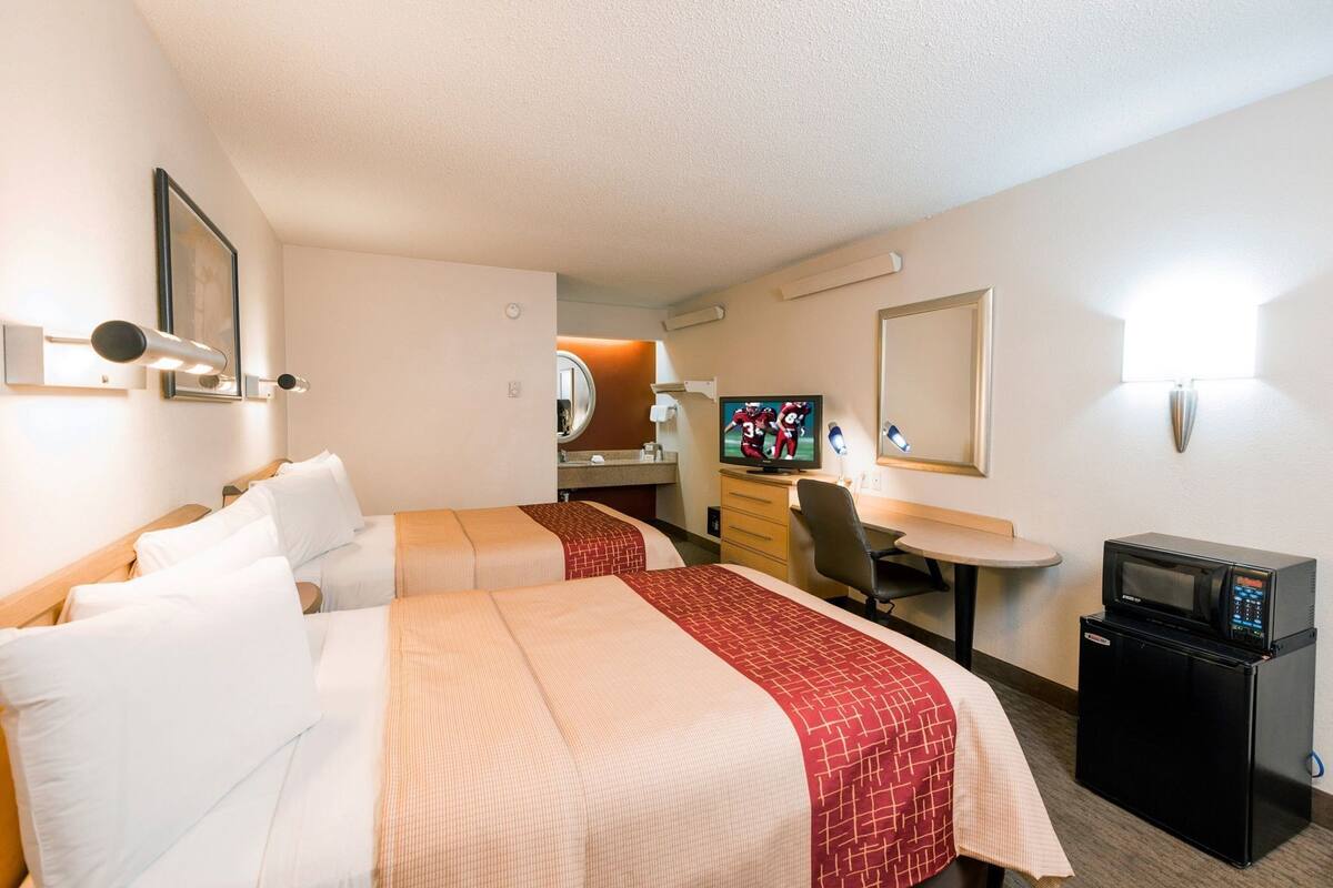 Une chambre d’hôtel avec deux lits, un bureau, une télévision et un four à micro-ondes.