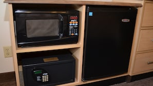 Una cocina compacta con microondas y refrigerador integrados en un mueble de madera.