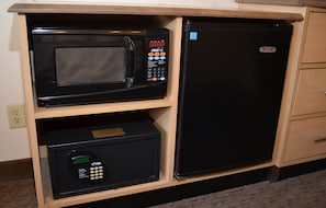 A compact kitchen with a microwave and a refrigerator built into a wooden cabinet.