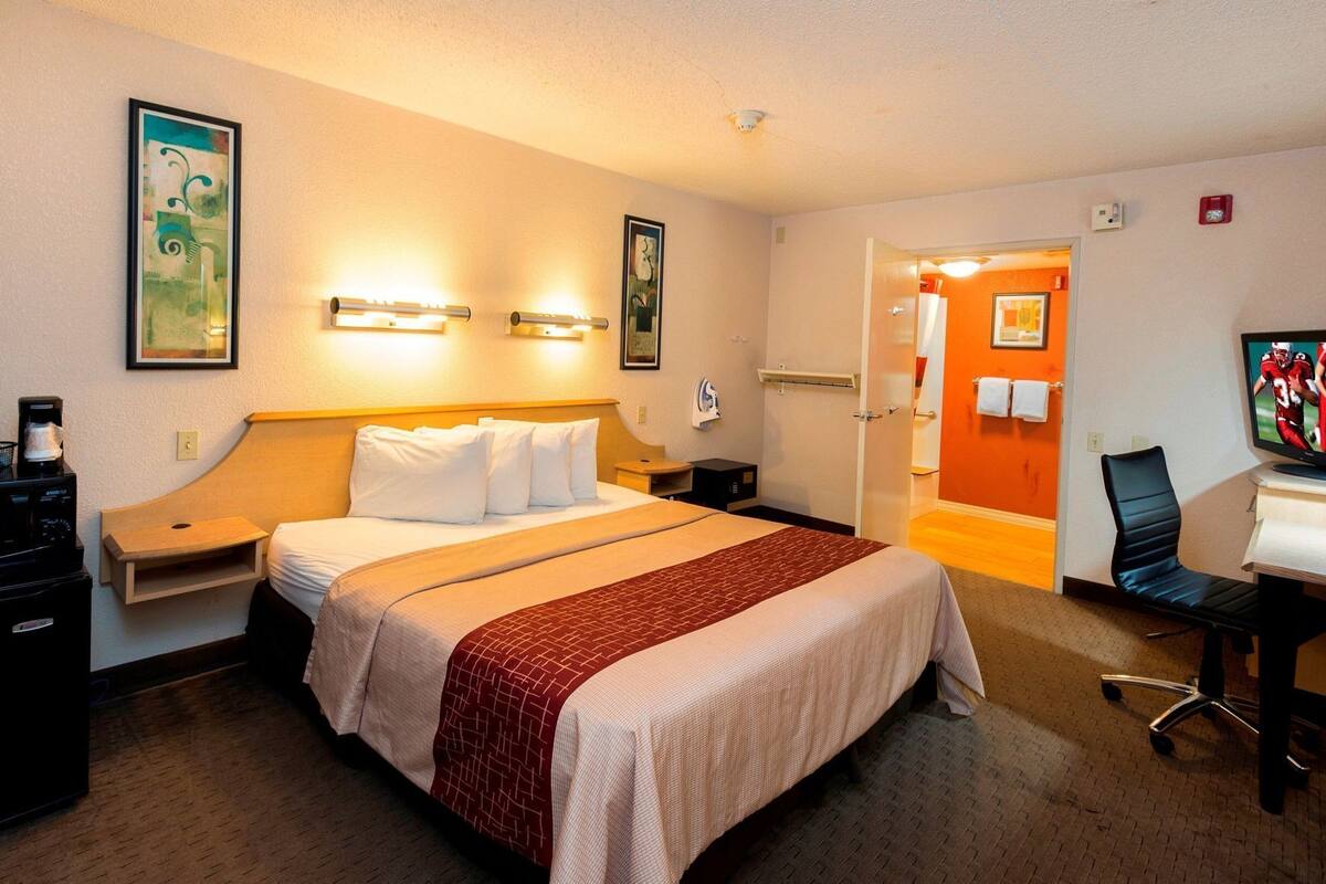 Une chambre d’hôtel comprenant un lit, des tables de chevet, un bureau, une chaise et un téléviseur.