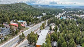 An aerial view of a town with a main road, buildings, and a forested area.