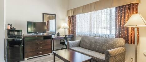 A compact living space with a sofa, a small table, a television, a microwave, and a cabinet.