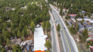 An aerial view of a residential area with a main road, houses, and a large building with a white roof.
