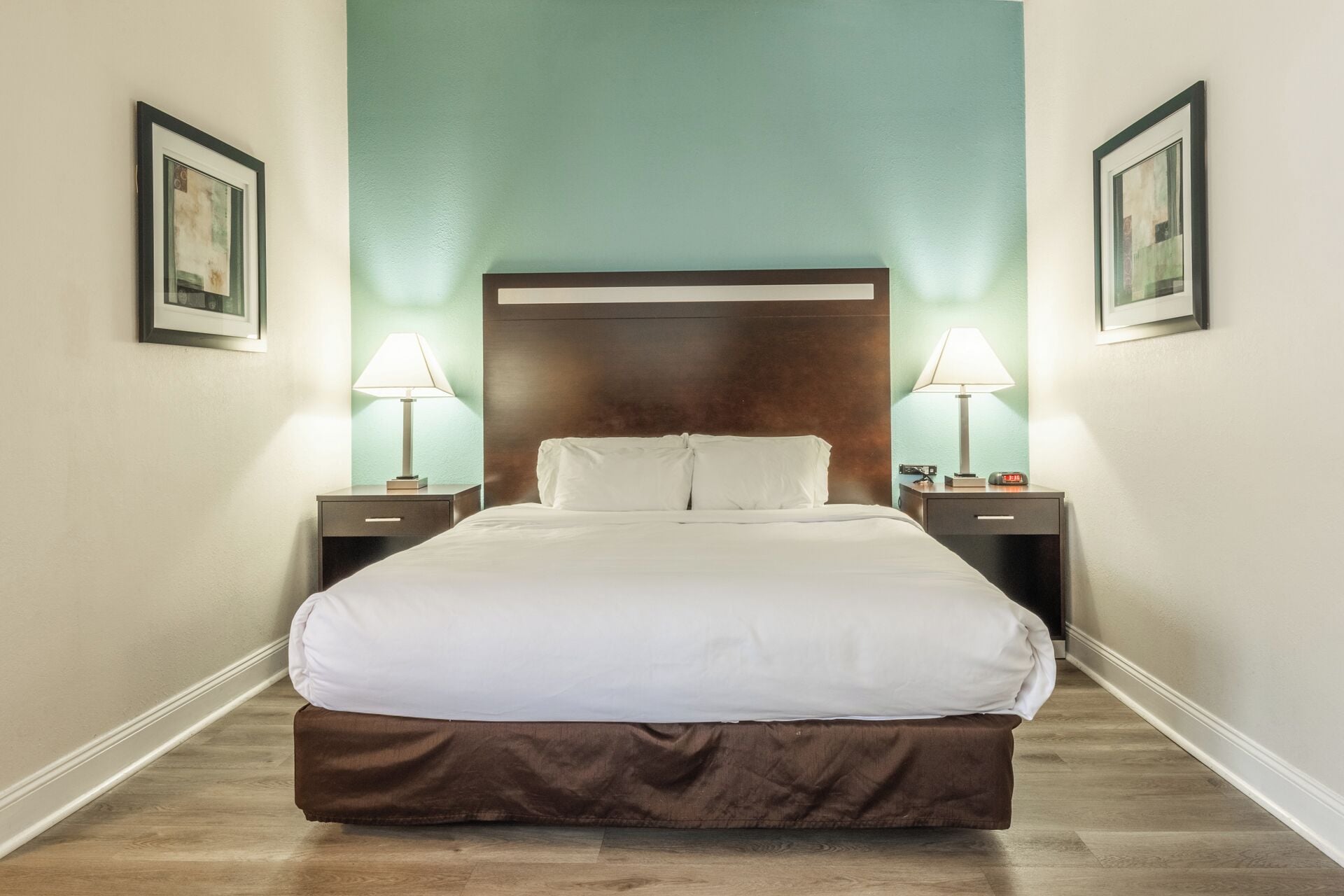 Ein Hotelzimmer mit einem großen Bett, zwei Nachttischen und einem Beistelltisch mit einer Lampe.