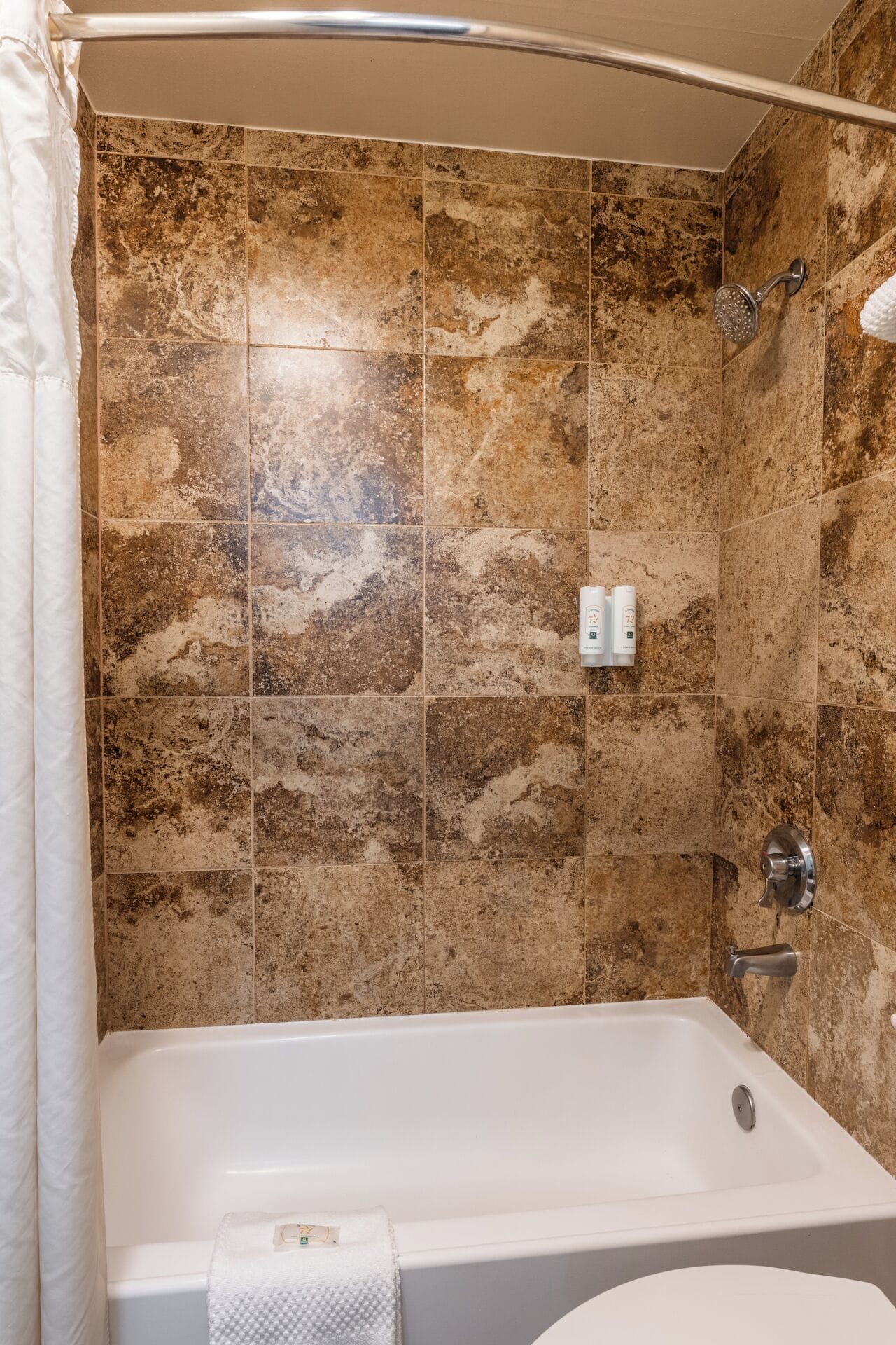 A bathroom with a bathtub, shower, and tiled walls.
