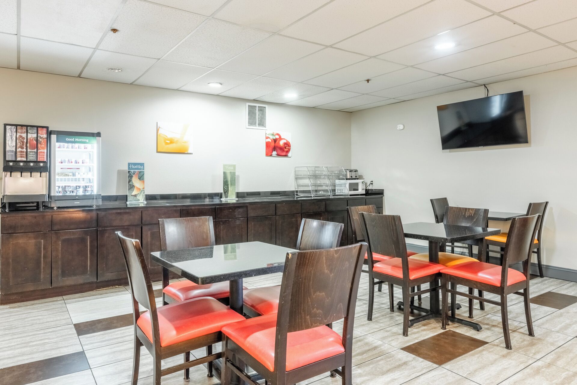 A restaurant with a counter, seating area, and a TV mounted on the wall.