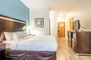 Cozy retreat with a neatly made bed, bedside lamp, and TV on a dresser, perfect for a restful stay.