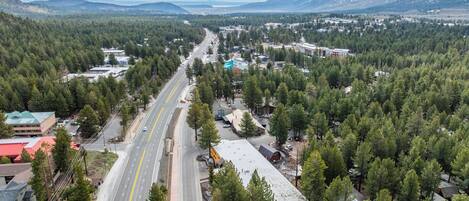 An aerial view of a town with a main road, buildings, and a mountain in the background.