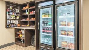 A self-service beverage station with refrigerated drink dispensers and shelves stocked with snacks and beverages. - Quality Inn Near Mammoth Mountain Ski Resort (Mammoth Lakes)