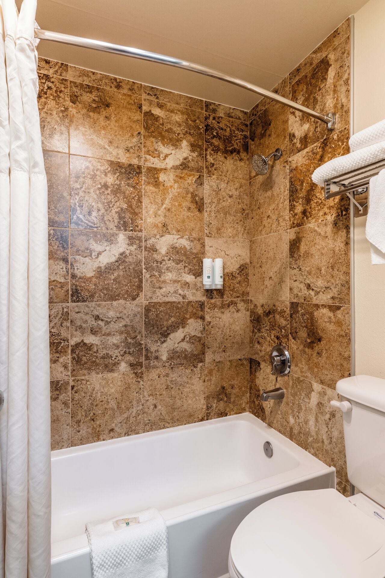 A bathroom with a bathtub, toilet, and shower area.