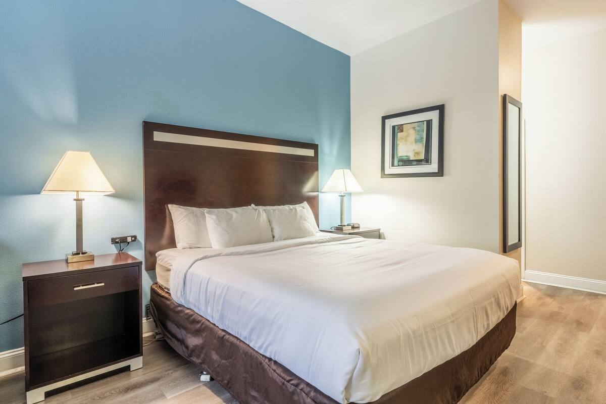 A neatly made bed with white linens, a dark headboard, and two bedside lamps.