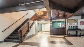 A spacious lobby with a wooden staircase, a reception desk, and a coffee station. - Quality Inn Near Mammoth Mountain Ski Resort (Mammoth Lakes)