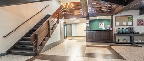 Un vestíbulo amplio con una escalera de madera, un mostrador de recepción y una estación de café.