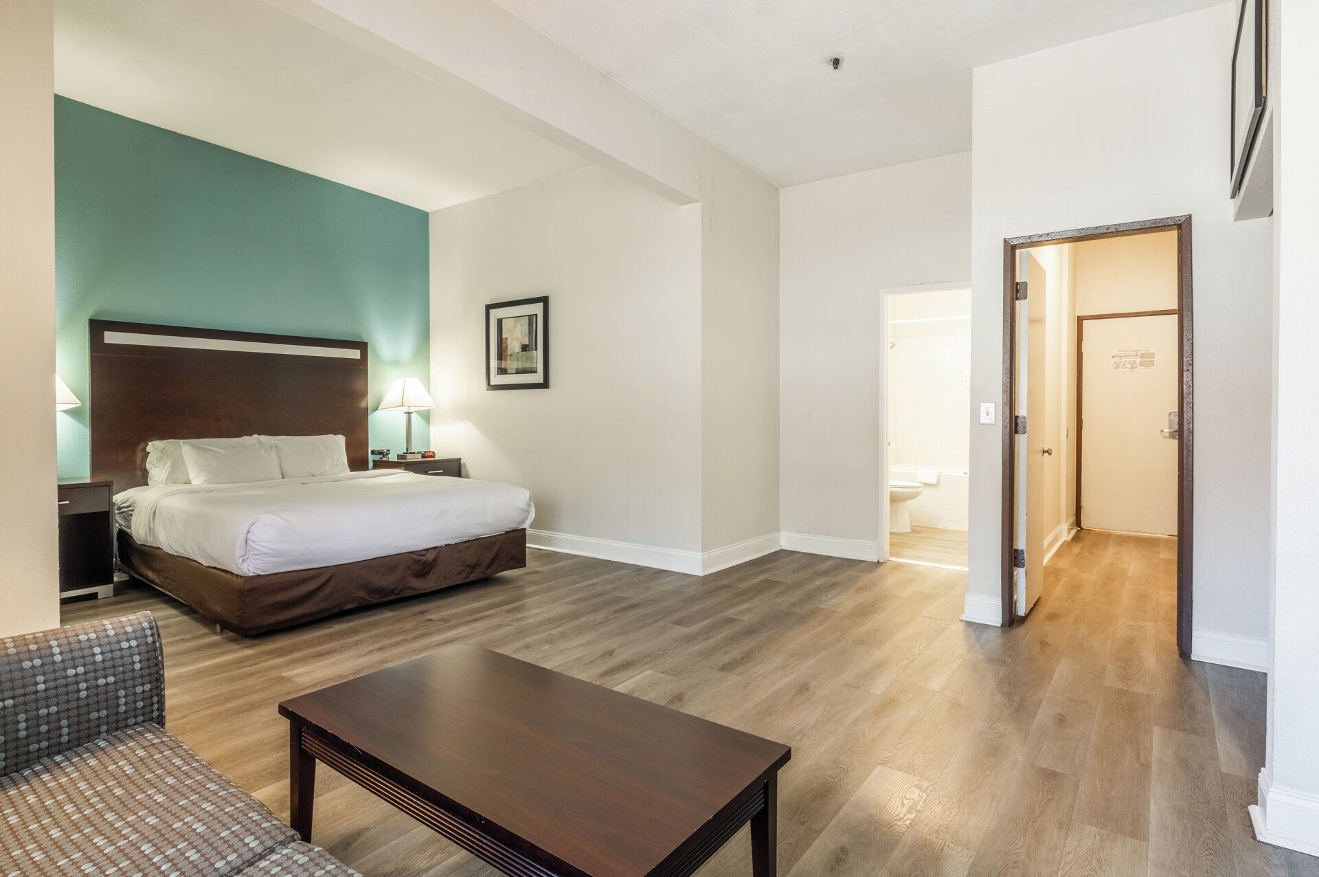 Ein Hotelzimmer mit Bett, Nachttisch, Lampe und einem gerahmten Bild an der Wand.