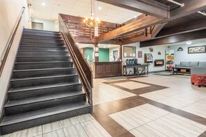 Step into a warm and inviting lobby with a grand staircase, reception desk, and cozy fireplace.