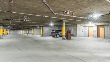 Un parking à plusieurs niveaux, avec des piliers en béton, une poubelle et un véhicule stationné au centre.