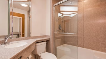 A modern bathroom with a granite countertop, a glass-enclosed shower, and a white toilet.