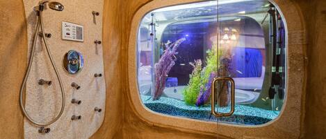 A bathroom with a shower, a glass-enclosed aquarium, and a bathtub.