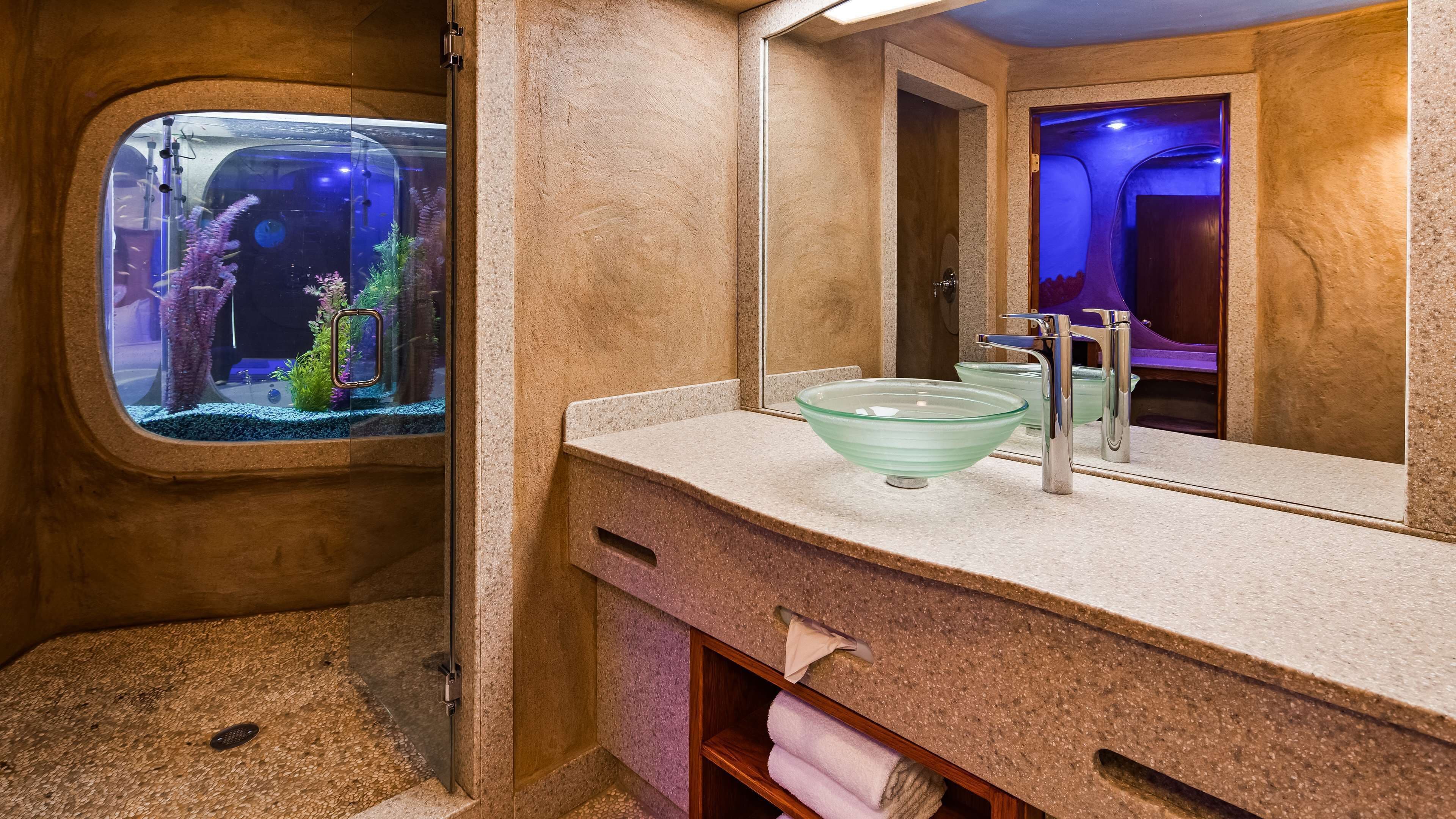 A bathroom with a large window, a glass bowl sink, a mirror, and a towel rack.