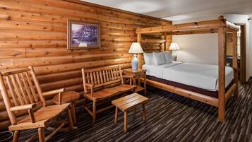 A wooden cabin-style room with a four-poster bed, wooden furniture, and a framed picture on the wall.