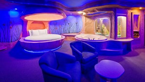 A modern spa room with a circular bed, a bathtub, and two chairs. - Best Western Galena Inn & Suites (Galena)