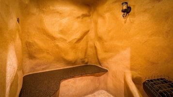 A stone bench in a rustic, textured room with a single wall-mounted light fixture.