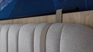A close-up of a textured, light-colored sofa with a wooden panel and a black horizontal bar above it.