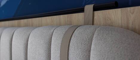 A close-up of a textured, light-colored sofa with a wooden panel and a black horizontal bar above it.
