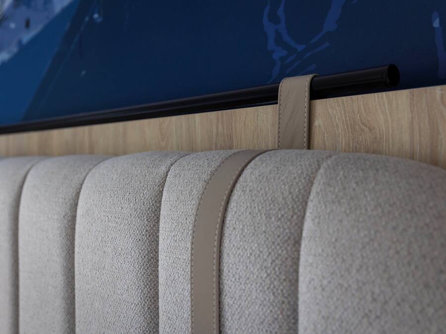 A close-up of a textured, light-colored sofa with a wooden panel and a black horizontal bar above it.