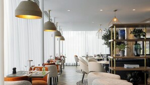 Een moderne eethoek met hoge plafonds, hanglampen en diverse zithoeken.