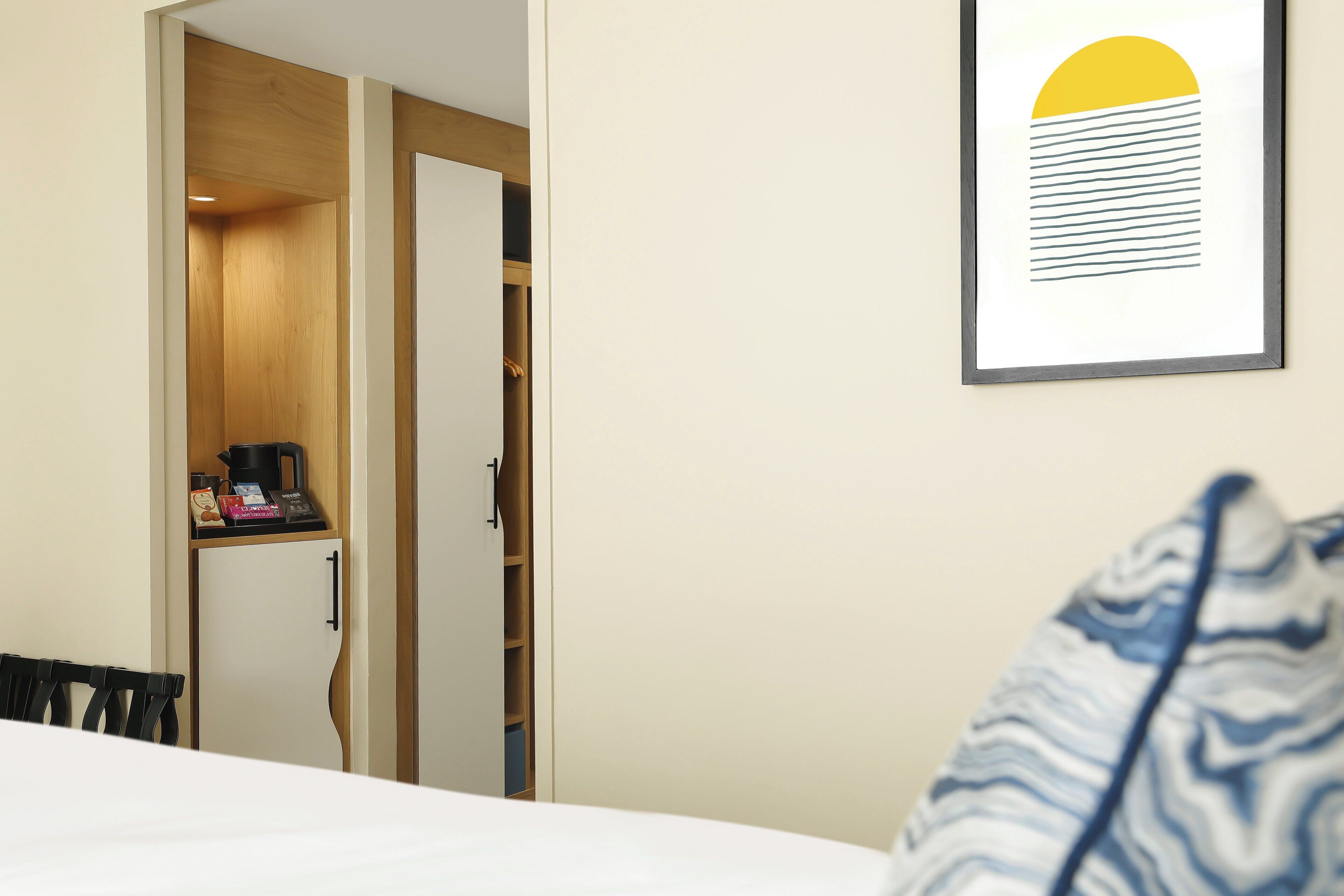 Een hotelkamer met een bed, een bureau met een koffieapparaat en een kledingkast.